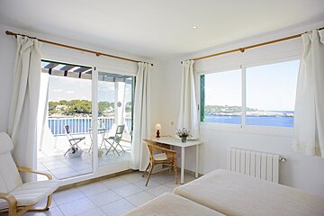 A bedroom with a sliding glass door leading to a balcony overlooking the ocean