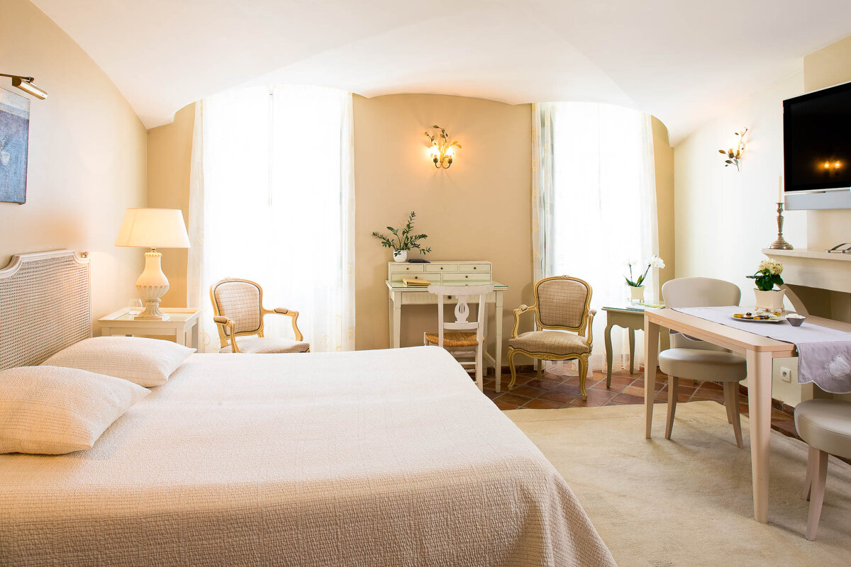 A bedroom with a large bed a desk and chairs