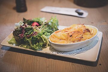 A white plate with a casserole and a salad on it