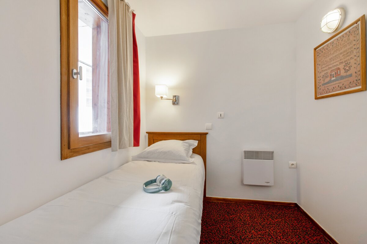 A small bedroom with a single bed and a picture on the wall