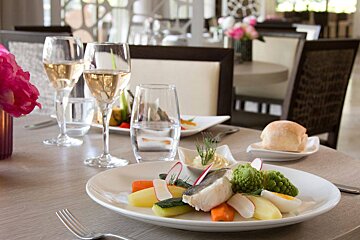 A plate of food sits on a table next to a glass of wine