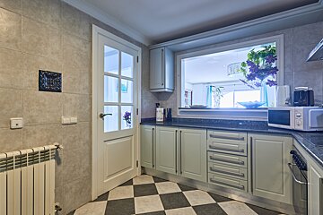 A kitchen with white cabinets and a black and white checkered floor