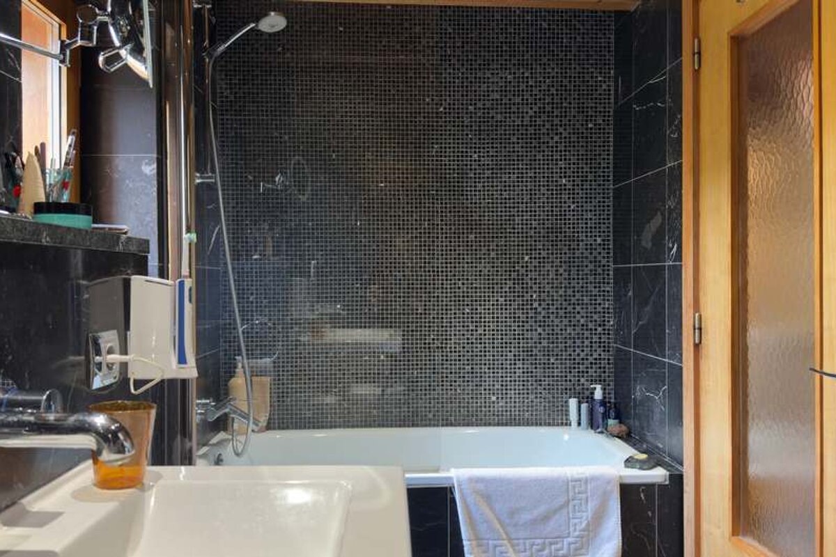A bathroom with black tiles and a bathtub