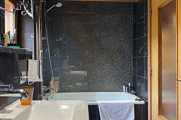 A bathroom with black tiles and a bathtub
