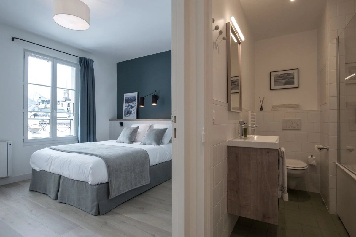 A bedroom with a bed and a bathroom with a sink