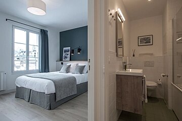 A bedroom with a bed and a bathroom with a sink