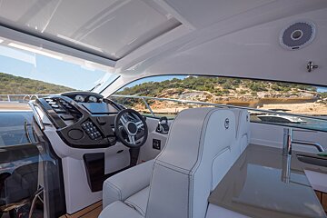 The inside of a boat with a steering wheel and a sink