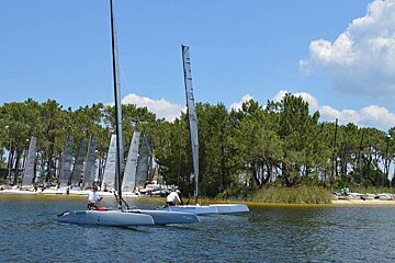 sail boats in the lake with tree lined shores