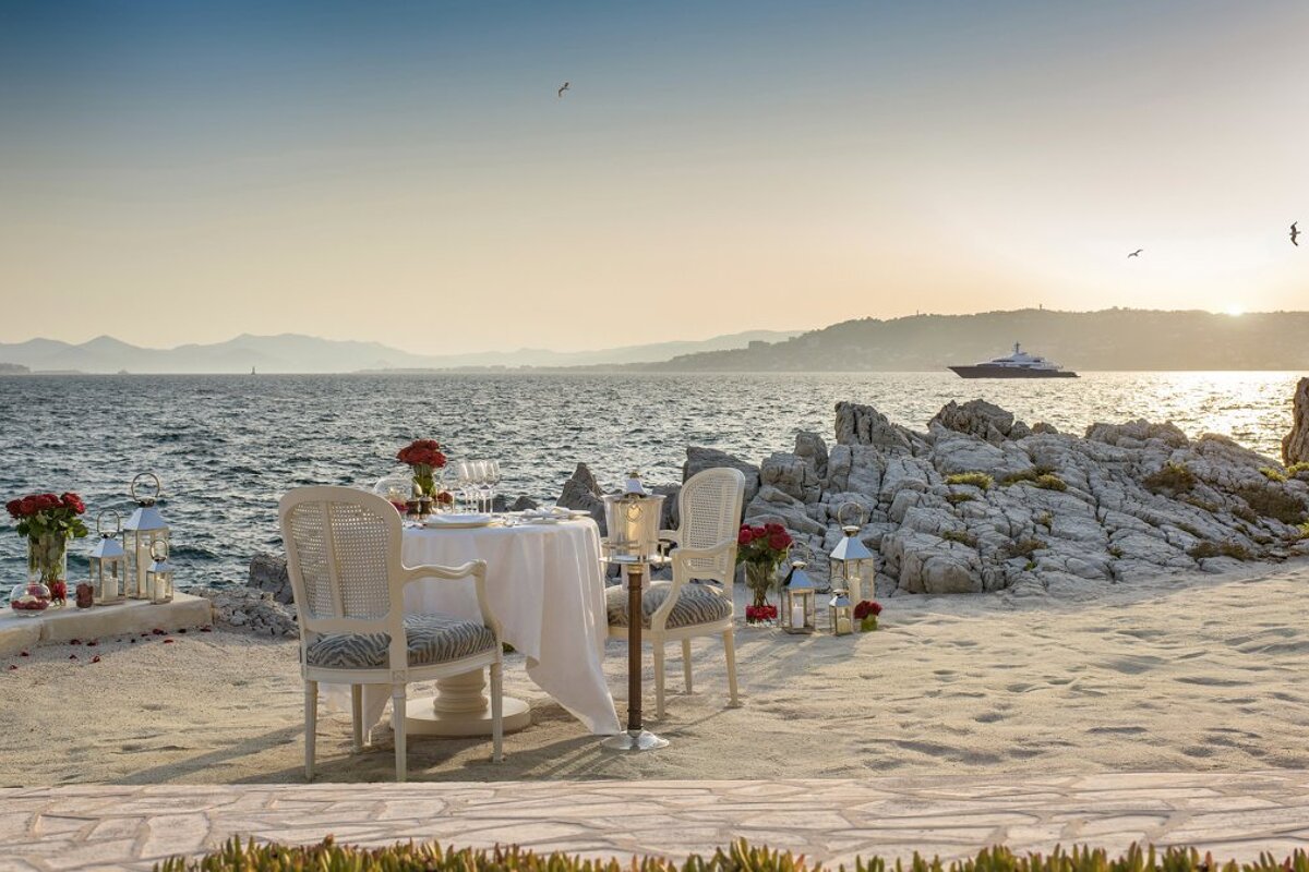 A table and chairs on the beach with a boat in the background