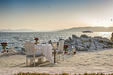 A table and chairs on the beach with a boat in the background