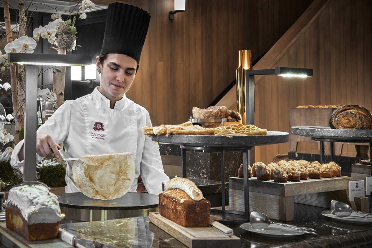 A chef wearing a uniform that says l' etoile prepares food