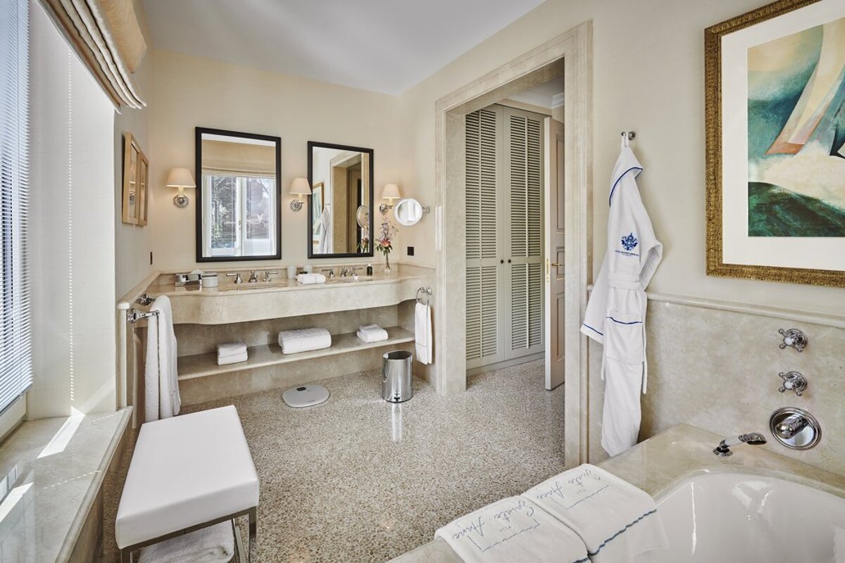 A bathroom with a bathtub and two mirrors and a robe that says ' la petite comtesse marie ' on it