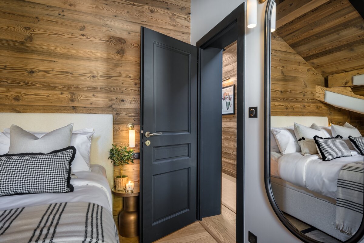 A bedroom with a black door and a mirror