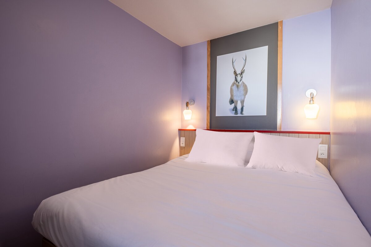 A bed with a picture of a deer on the wall above it