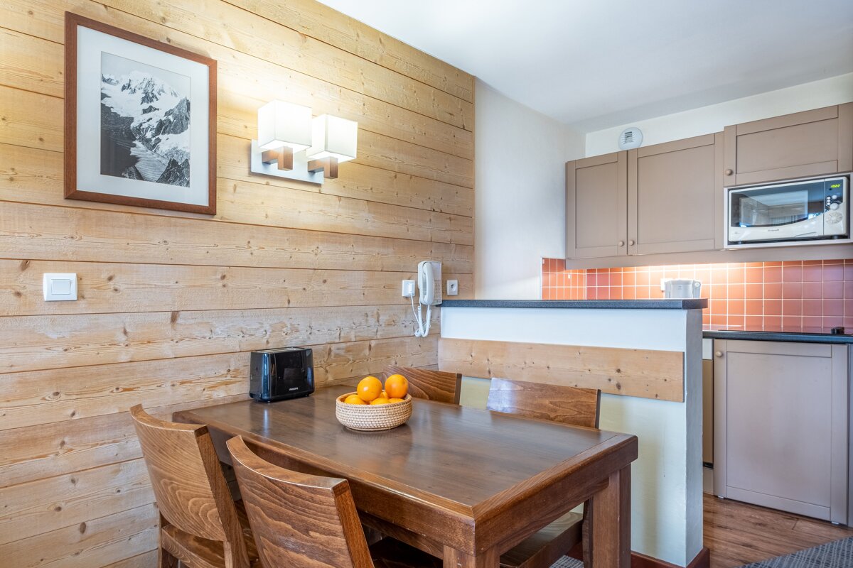 A wooden table with a bowl of oranges on it