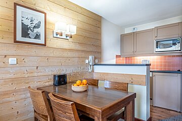 A wooden table with a bowl of oranges on it