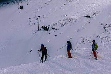 three skiers looking at a line