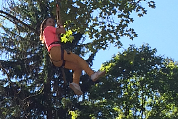 a girl in a climbing harness in the trees