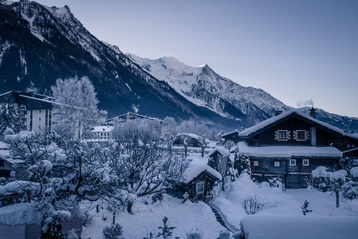 A snowy house with a mountain in the background