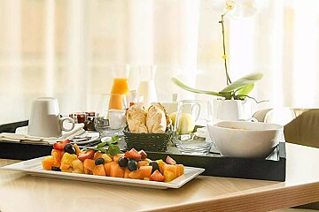 A tray of fruit and bread sits on a table
