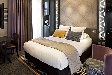 A hotel room with a bed and a chair