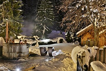 Two people in a hot tub in the snow at night