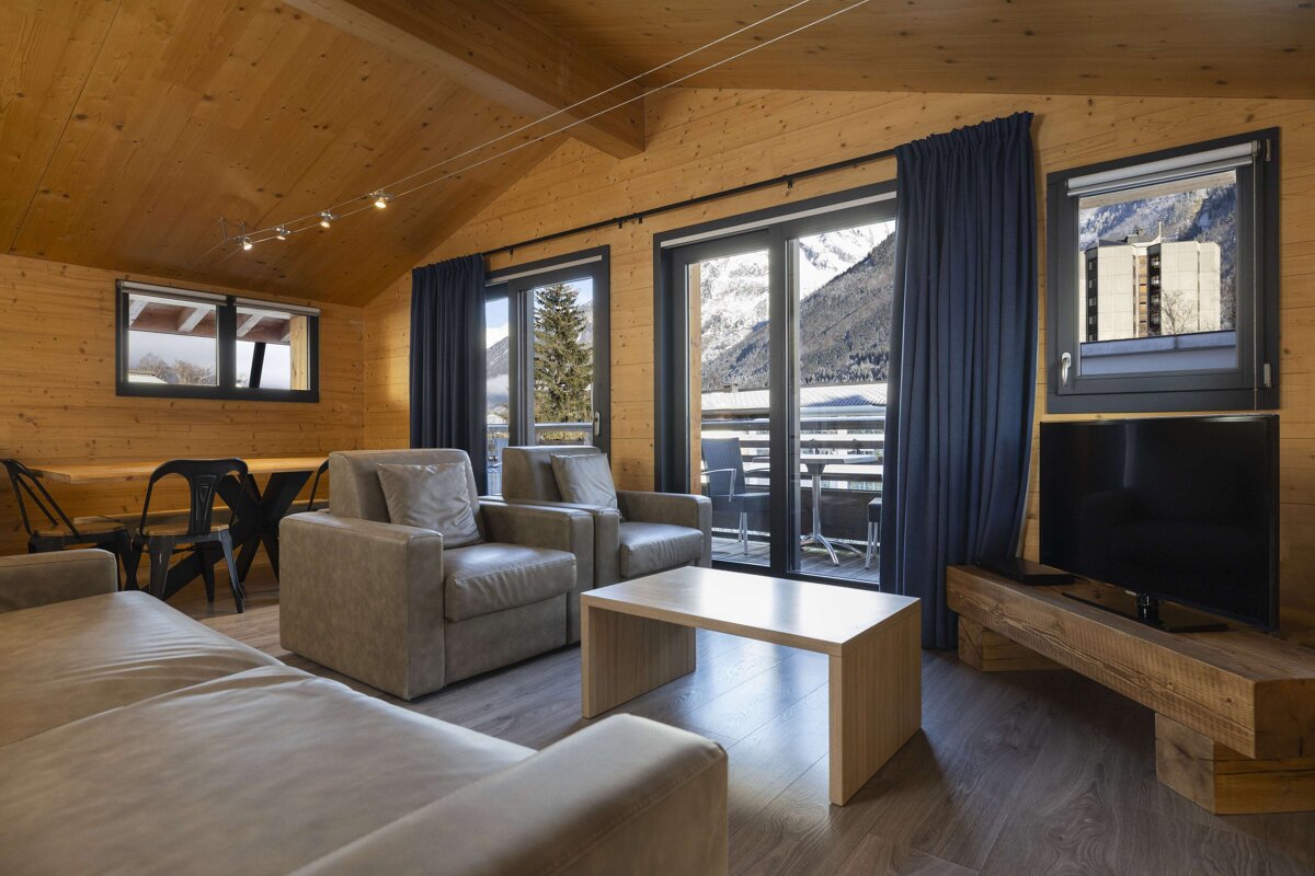 A living room with a couch two chairs and a flat screen tv