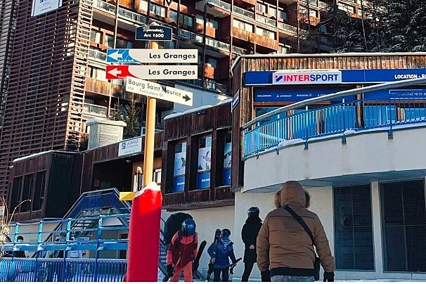 A snowy ski resort scene with directional signs pointing to 