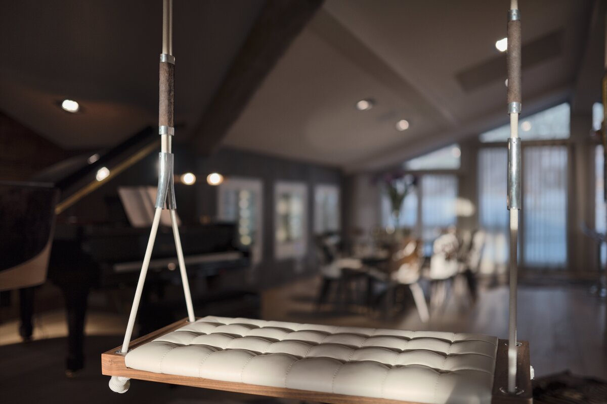 A swing in a living room with a piano in the background