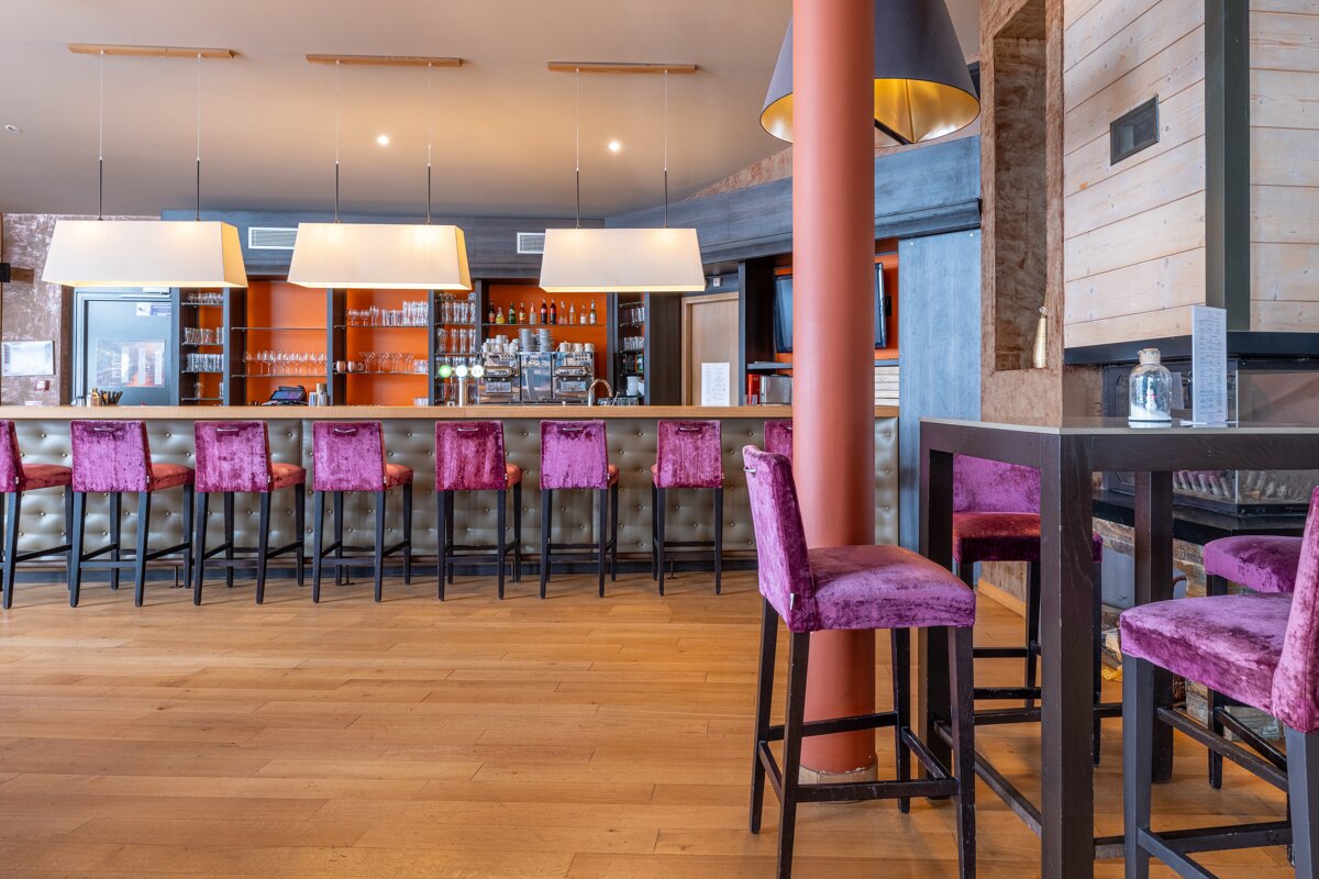 A bar with purple chairs and tables in front of it