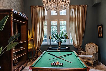 A pool table in a room with a chandelier above it