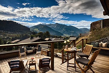 A table and chairs on a deck overlooking mountains