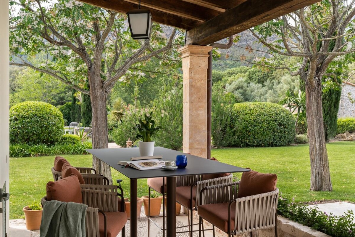 A table with a cup of coffee on it sits on a porch