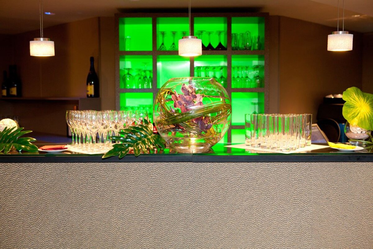 A bar with lots of glasses and a vase of flowers