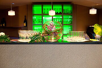 A bar with lots of glasses and a vase of flowers