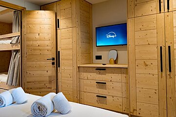 A bedroom with bunk beds and a flat screen tv that says disney +