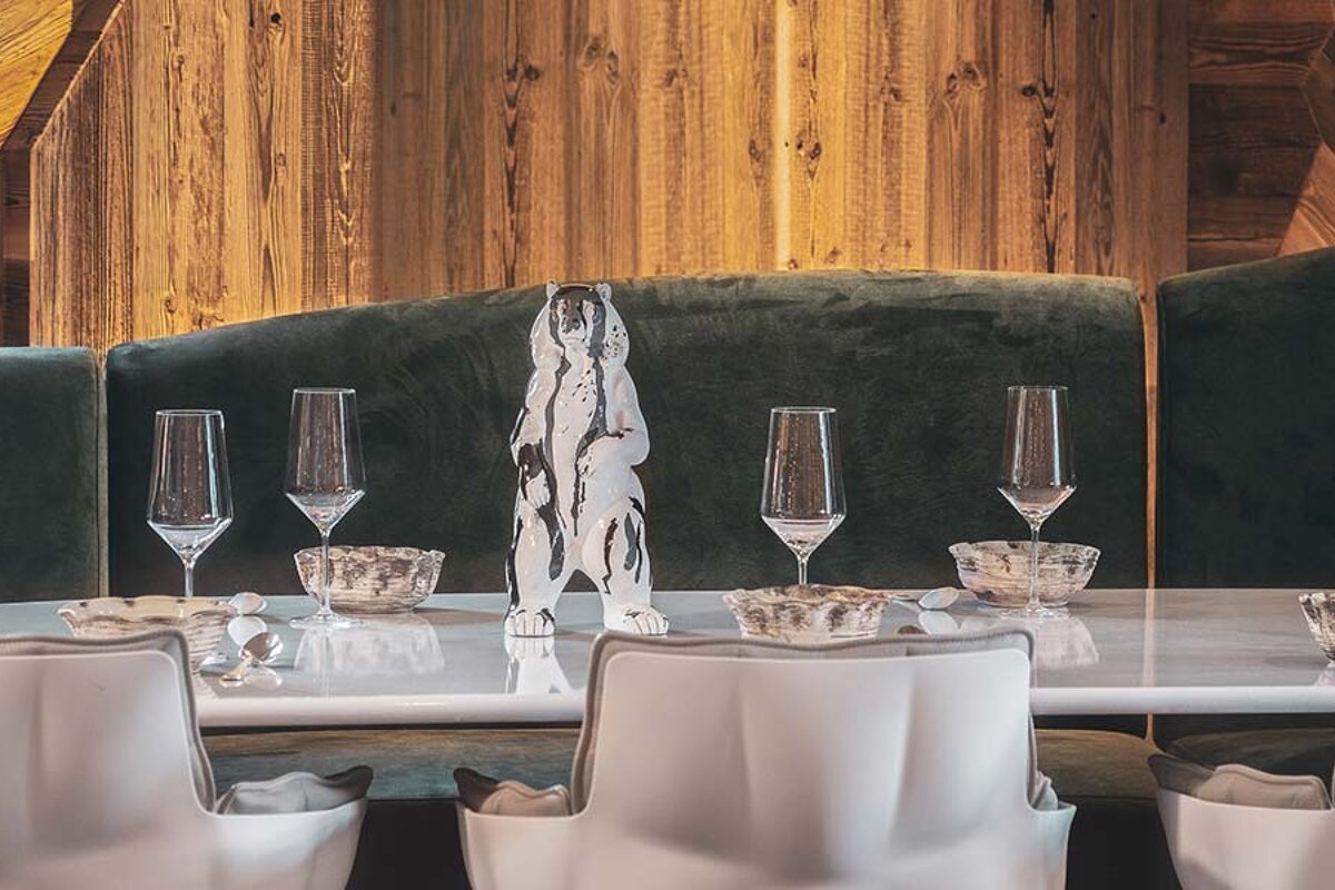 A statue of a bear sits on a table next to wine glasses