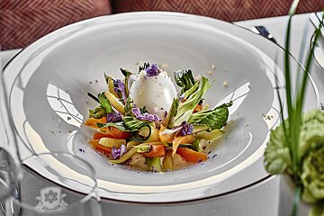 A white plate with vegetables and an egg on top