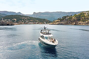 A boat is floating on a body of water with mountains in the background
