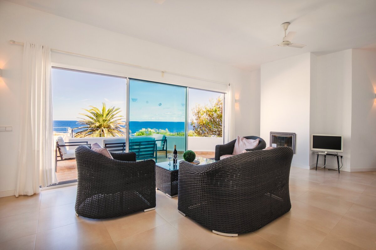 A living room with a sliding glass door leading to a balcony overlooking the ocean