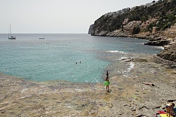 people in the clear water at Cala Llamp
