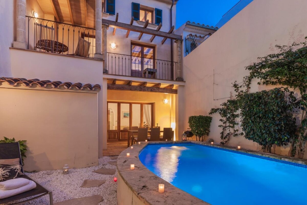 A swimming pool with candles around it in front of a house