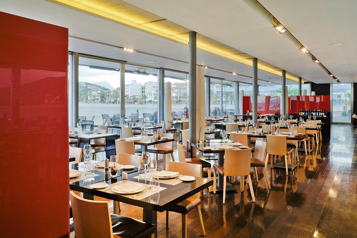 A restaurant with tables and chairs and a red wall