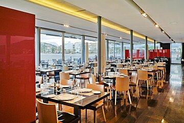 A restaurant with tables and chairs and a red wall