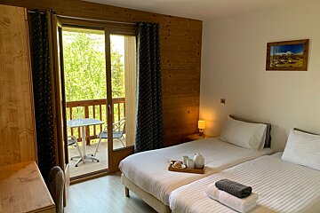 A hotel room with two beds and a balcony