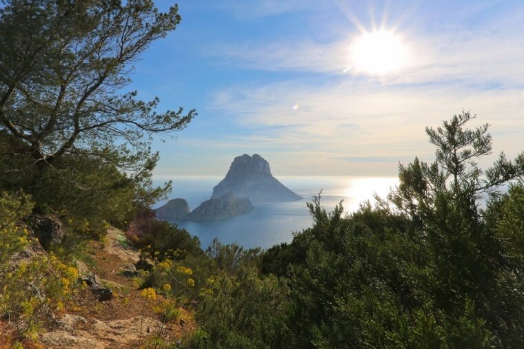 The sun is shining brightly over the ocean and mountains