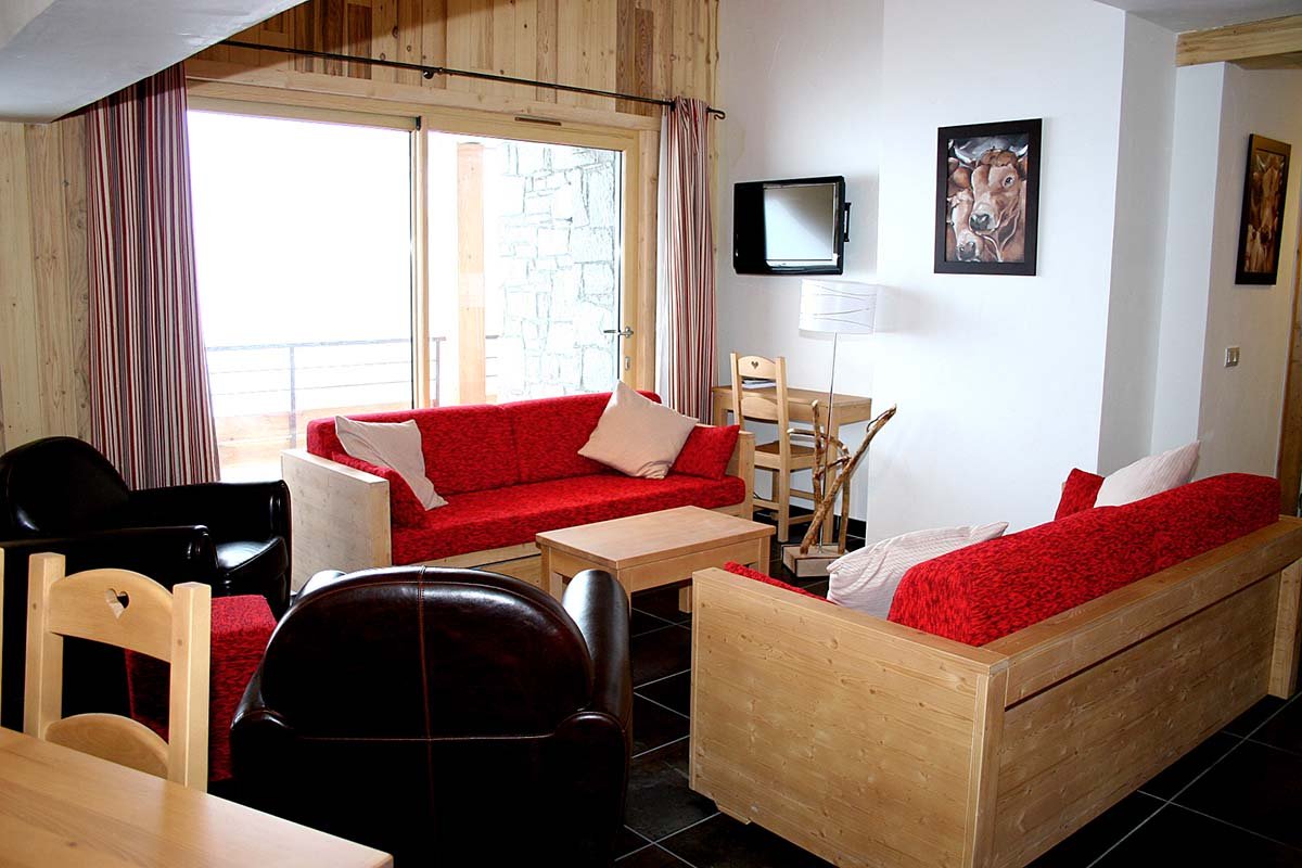 A living room with a red couch and a picture of a dog on the wall