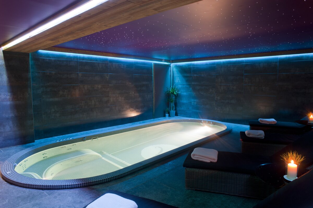 A jacuzzi in a dark room with a purple ceiling