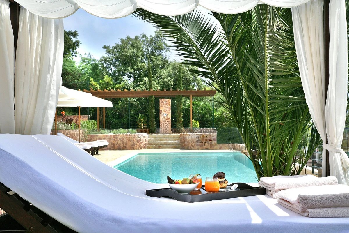 A tray of fruit sits on a lounge chair next to a pool