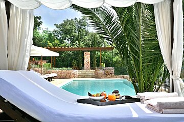 A tray of fruit sits on a lounge chair next to a pool